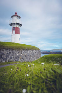 Lighthouse by sea against sky