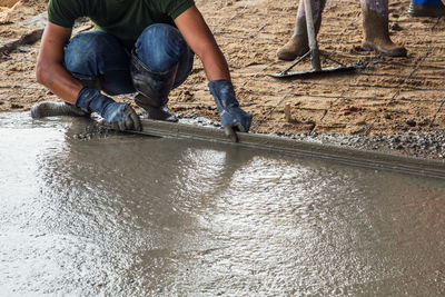 Low section of workers working with cement on construction site