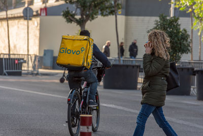 People riding bicycle on road in city