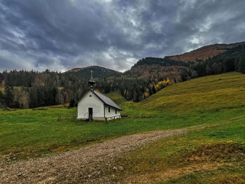 Built structure on field by mountain against sky