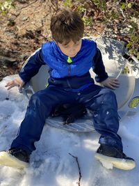 High angle view of boy sitting on snow field