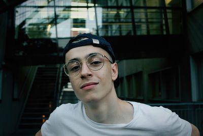 Close-up portrait of young man standing against building in city