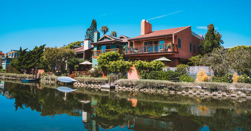 Buildings by lake against blue sky