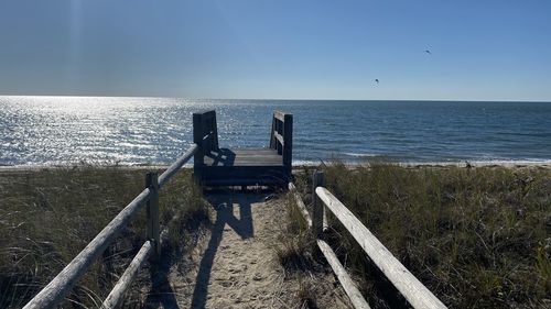 Bench on beach against sky