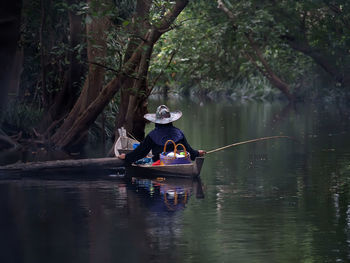 Rear view of woman fishing while sitting on boat