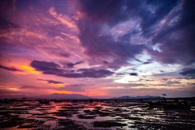 Scenic view of lake against cloudy sky during sunset