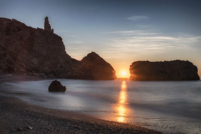 Scenic view of rocks in sea against sky during sunset