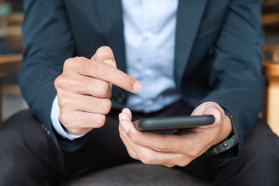 Midsection of man using mobile phone