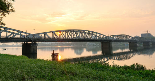 Bridge over river against sky during sunset