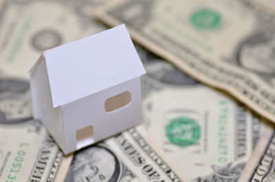 Close-up of model house and paper currencies representing home ownership