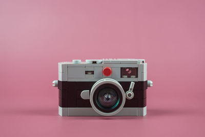 Close-up of camera on table against pink background