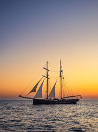 Sailboat sailing on sea against clear sky during sunset