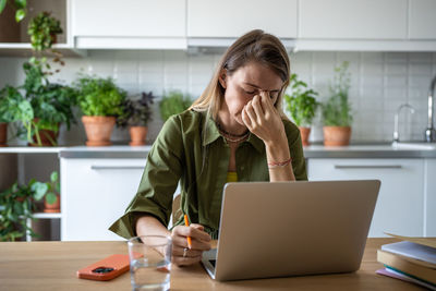 Young woman using laptop while sitting on table