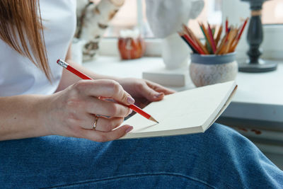 A pencil in a woman's hands. drawing on a sheet of paper with a simple pencil. 