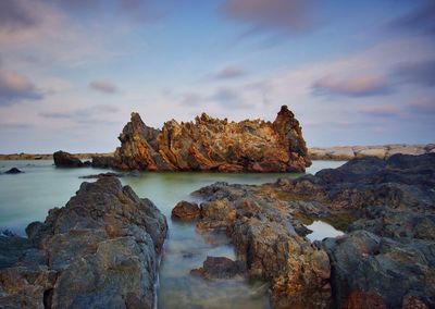 Rock formations on shore against sky