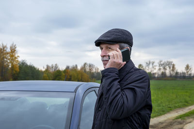 Young man using smart phone against sky