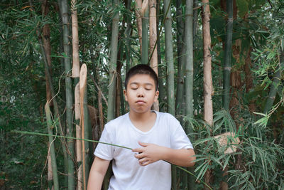 Teenage boy standing at forest