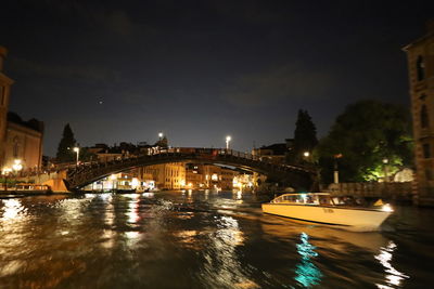 Illuminated bridge over river at night