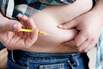Midsection of young man injecting syringe