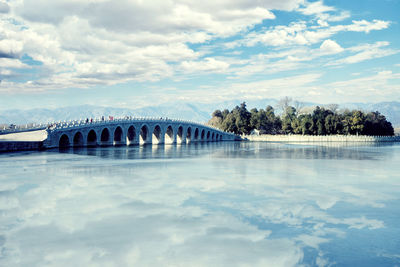 Bridge over river against cloudy sky