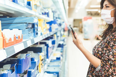 Side view of woman wearing mask standing in supermarket