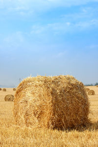 Hay bales on field against sky