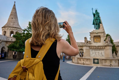 Rear view of woman standing against building