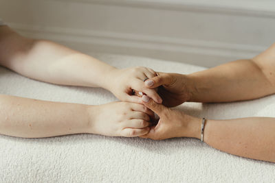 Mother and daughter holding hands on sofa at home