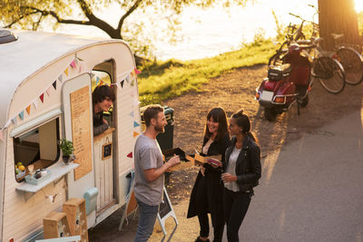 High angle view of owner looking at customers standing on street through food truck window