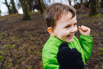 An excited young boy smiling as he plays in the woods