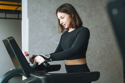 Young fitness brunette woman training for cardio equipment treadmill at gym