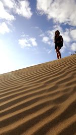 Low angle view of woman on sand dune against sky