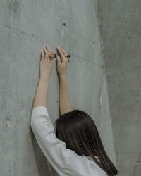 Side view of young woman wearing rose shape rings by wall