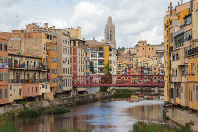 Buildings by river against sky in city