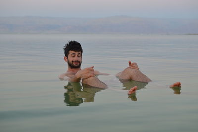 Young man with eyes closed relaxing in dead sea during sunset