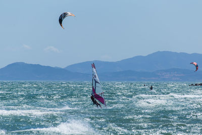 People kiteboarding and windsurfing against sky