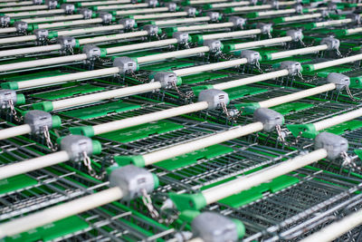 Many empty green shopping carts in row. row of parked trolleys in supermarket.