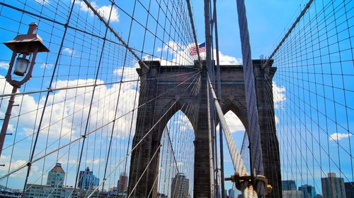 Low angle view of flag on bridge against cloudy sky