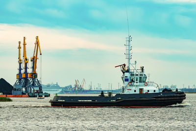 Cranes at commercial dock against sky