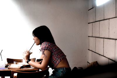 Full length of girl sitting on wall at home