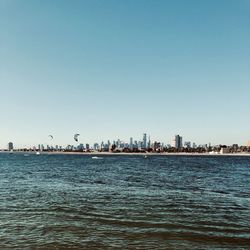 Sea and buildings against clear blue sky