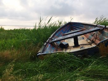 Abandoned boat on field against sky