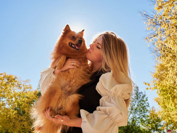 Low angle view of woman with dog against sky