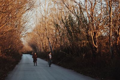 Rear view of people walking on footpath during autumn