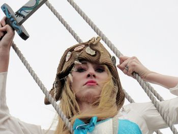 Portrait of young woman holding rope against white background