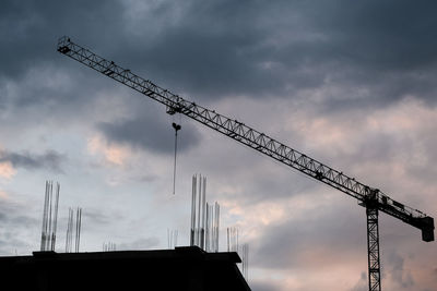 Low angle view of silhouette cranes against sky at sunset