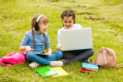 Girls learning over technologies while sitting on grass