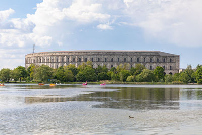 Reflection of building in lake against cloudy sky