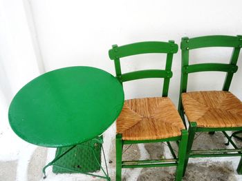 High angle view of empty chairs and table by wall