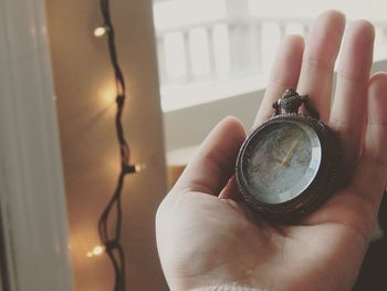 Close-up of hand holding navigational compass at home